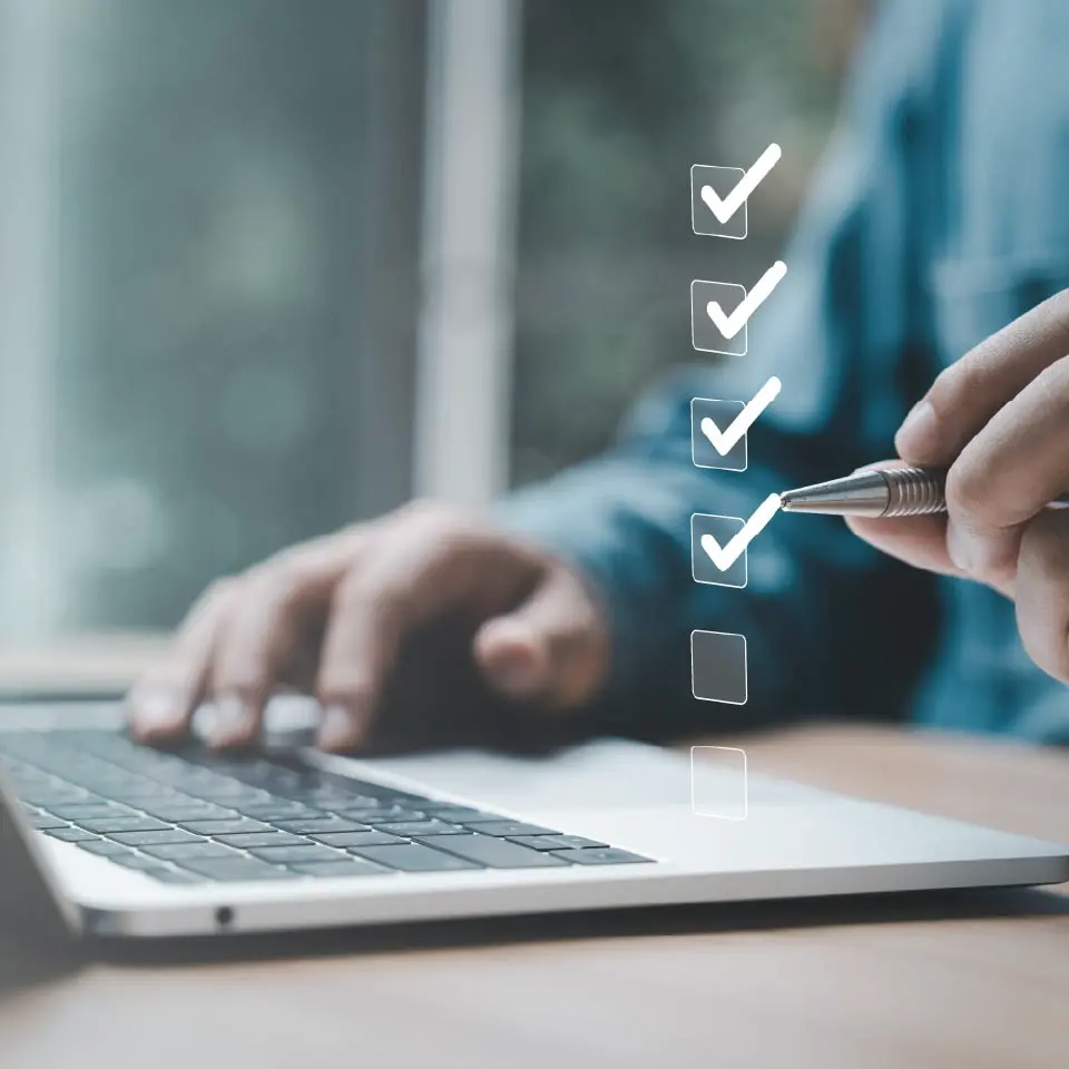Persona marcando una checklist digital en un portátil para evaluar y garantizar la seguridad en una comunidad de vecinos